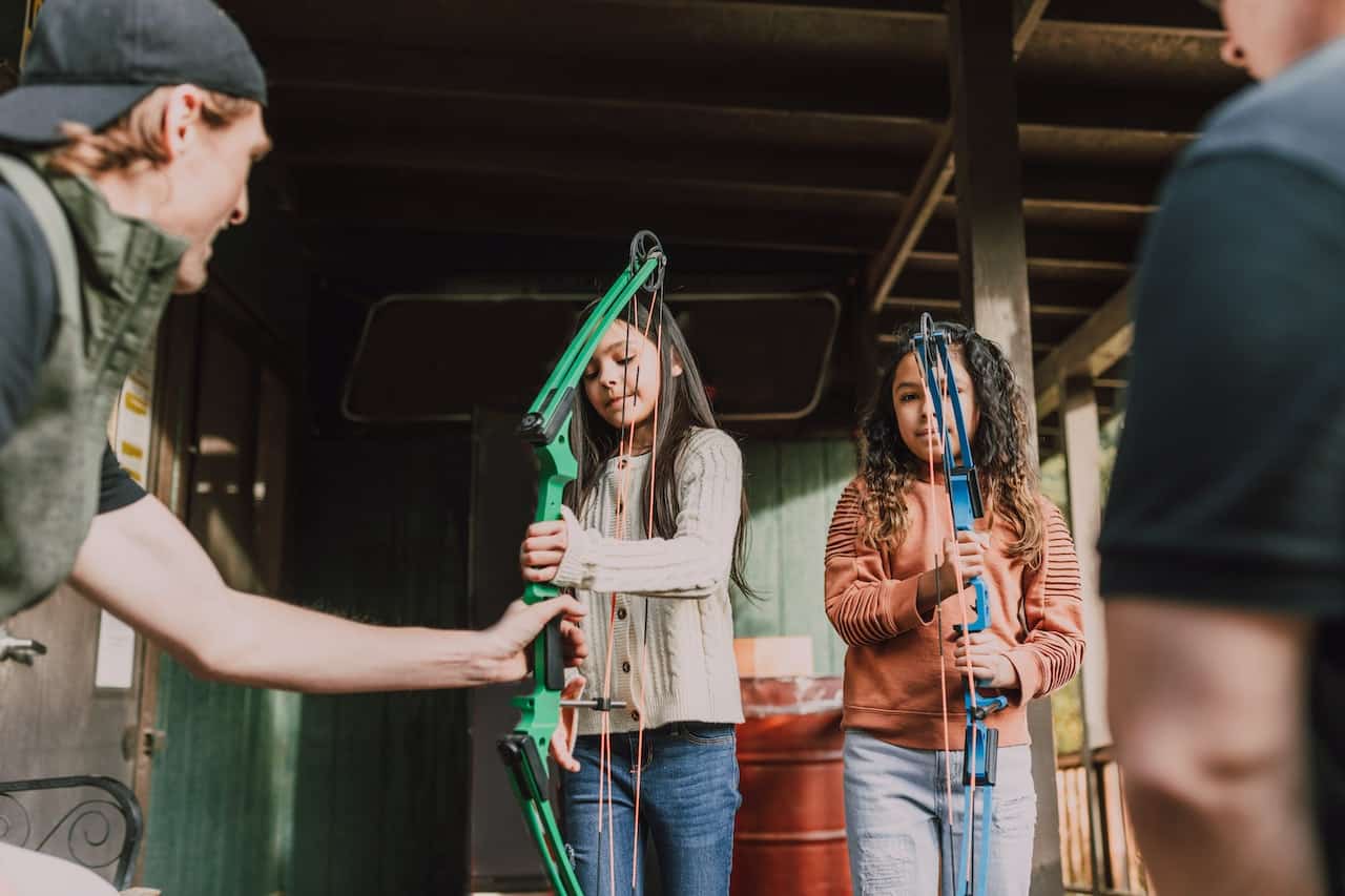 A coach introducing children to beginner archery equipment
